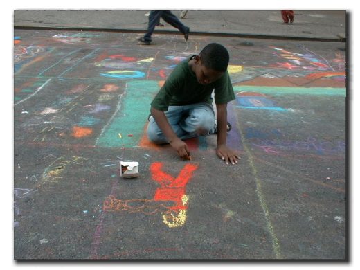 Picture of a little boy drawing with chalk on the street