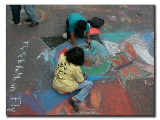 Picture of two children drawing with chalk on the street