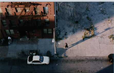Photo of lone individual walking down a street.  Photo taken from the roof of 310 East 102nd Street in the early 90s.