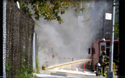 Photograph of New York City Fireman hosing down a stubborn electrical transformer fire at Metropolitan Hospital Center located at East 99th Street and First Avenue