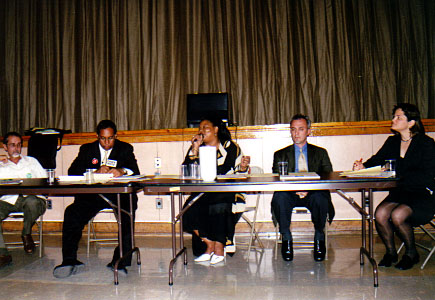 Picture of some of the candidates sitting behind tables at the Women of El Barrios first candidates debate.